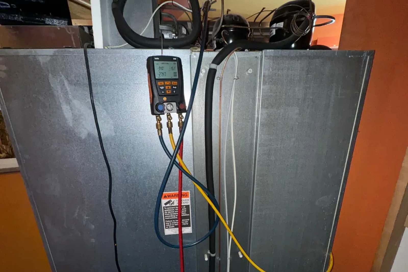 Technician running manifold gauge diagnostics on a refrigerator sealed system